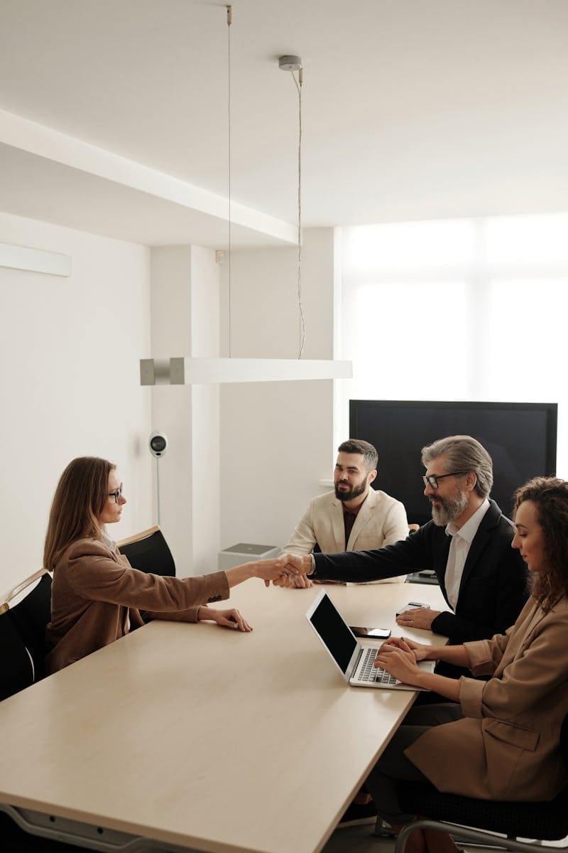 Business professionals engaging in a handshake across a conference table, signifying successful fintech consulting for private equity.